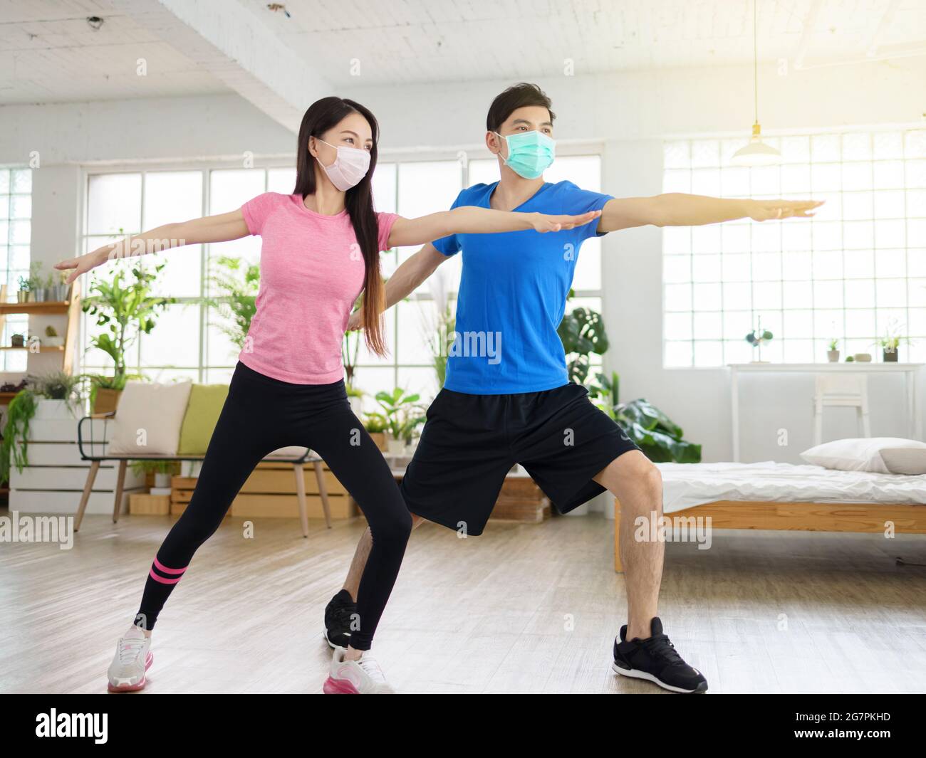 Young couple wear with medical masks and exercising at home. Stock Photo