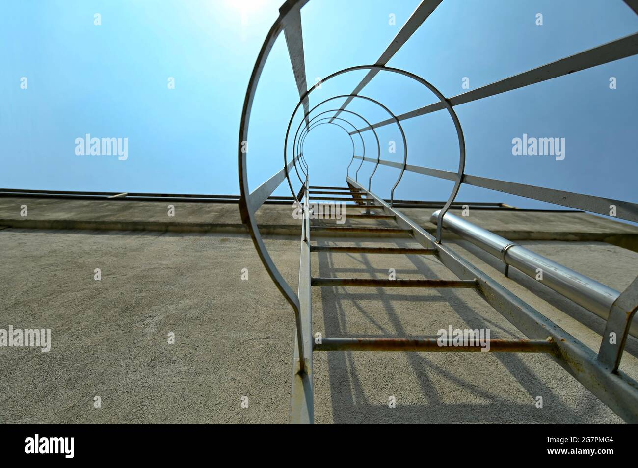 Low angle of metal escape ladder on a concrete wall under blue sky
