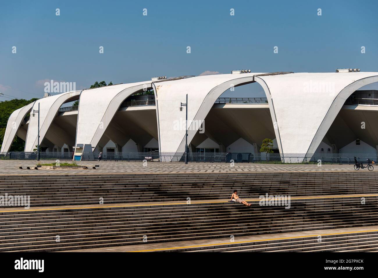 A man sunbathes on the steps in front of theThe Masachika Murata-designed athletics stadium inside Komazawa Olympic Park, Tokyo on 10 June 2021. The park was built for the 1064 Olympics and remains a popular leisure venue. Robert Gilhooly photo Stock Photo