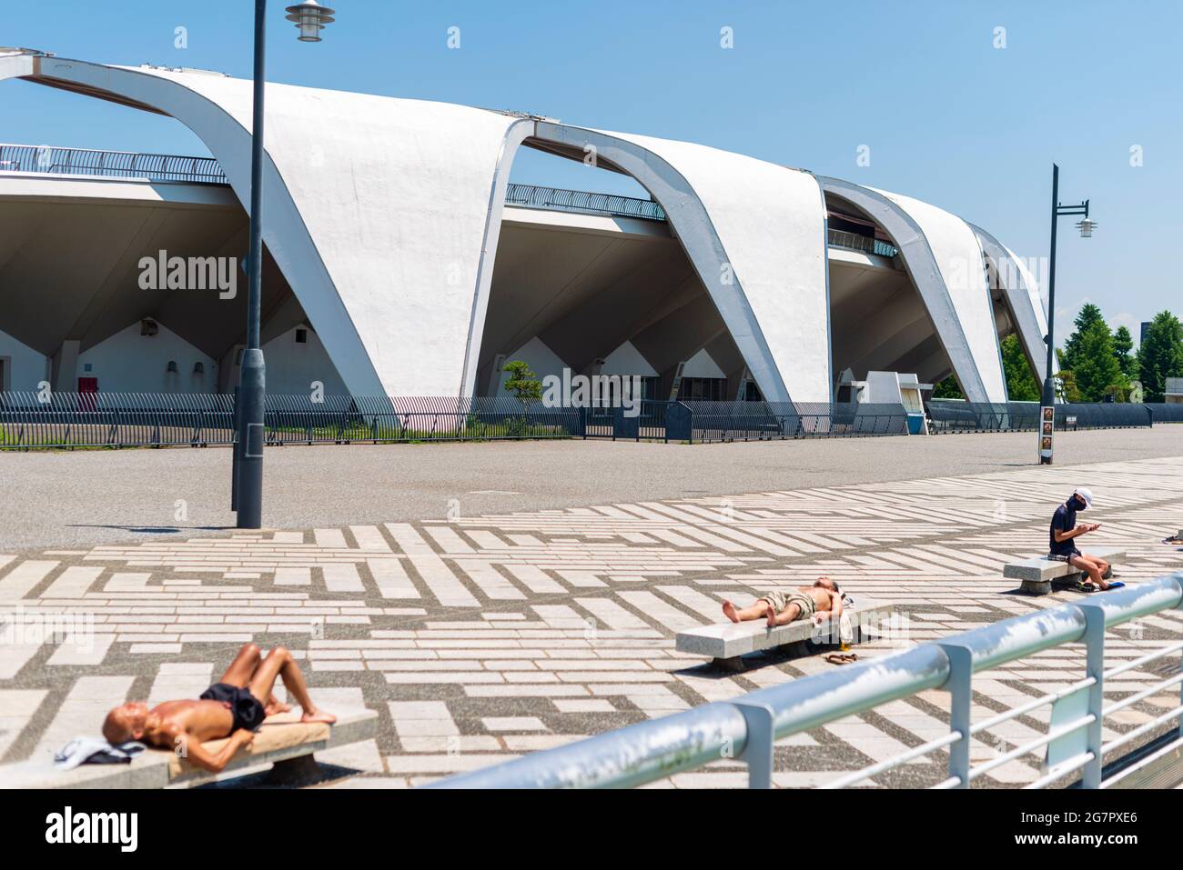 People sunbath in front of the athletics stadium inside Komazawa Olympic Park, Tokyo on 10 June 2021. The park was built for the 1964 Tokyo Olympics.  Robert Gilhooly photo Stock Photo