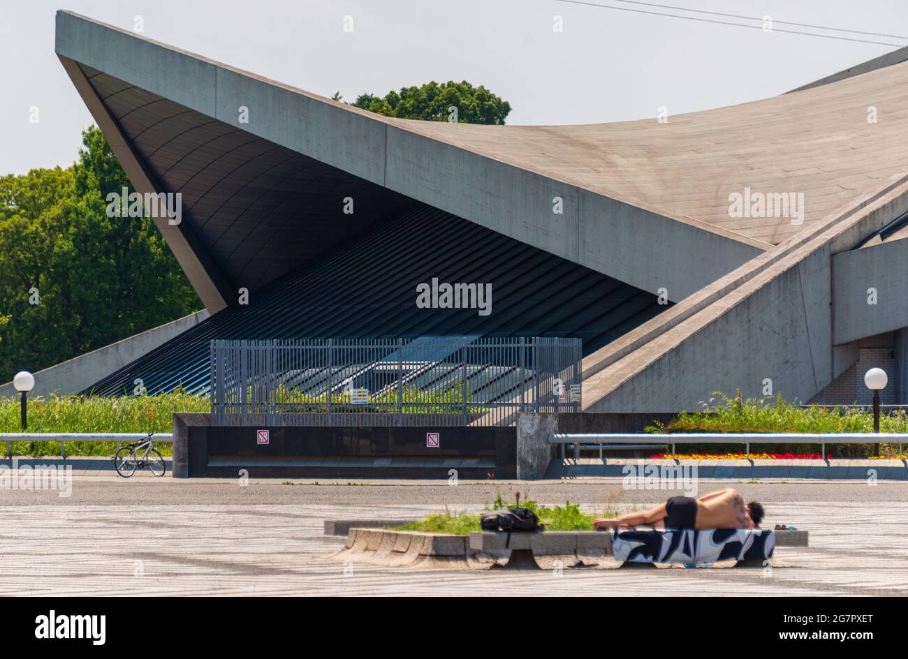 A man sunbathes in front of the gymnasium inside Komazawa Olympic Park, Tokyo on 10 June 2021. The park was built for the 1964 Tokyo Olympics. Robert Gilhooly photo Stock Photo