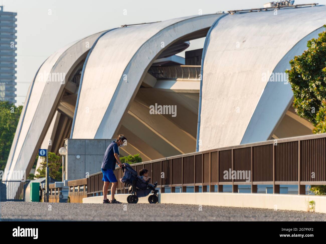 A man pushes his children past the athletics stadium inside Komazawa Olympic Park, Tokyo on 10 June 2021. The park was built for the 1964 Tokyo Olympics,  Robert Gilhooly photo Stock Photo