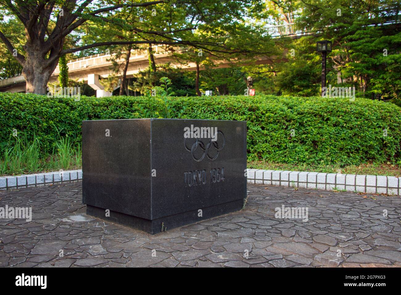 A memorial stone commemorating the 1964 Tokyo Olympics stands inside Yoyogi Park in Tokyo on 21 June 2021. The park was originally a US military housing complex, which was returned to Japan for the Olympics and turned into the athletes' village. A bronze legend on top of the memorial stone lists all of the facilities that were available to the 7000 athletes and entourage, including training facilities, a swimming pool, theater, sauna and dining hall. Robert Gilhooly photo Stock Photo