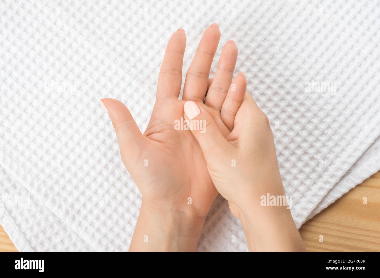 one female hand massages the other hand lying on a white towel with the open palm up. Closeup hand of person massage her hand from pain in healthy con Stock Photo