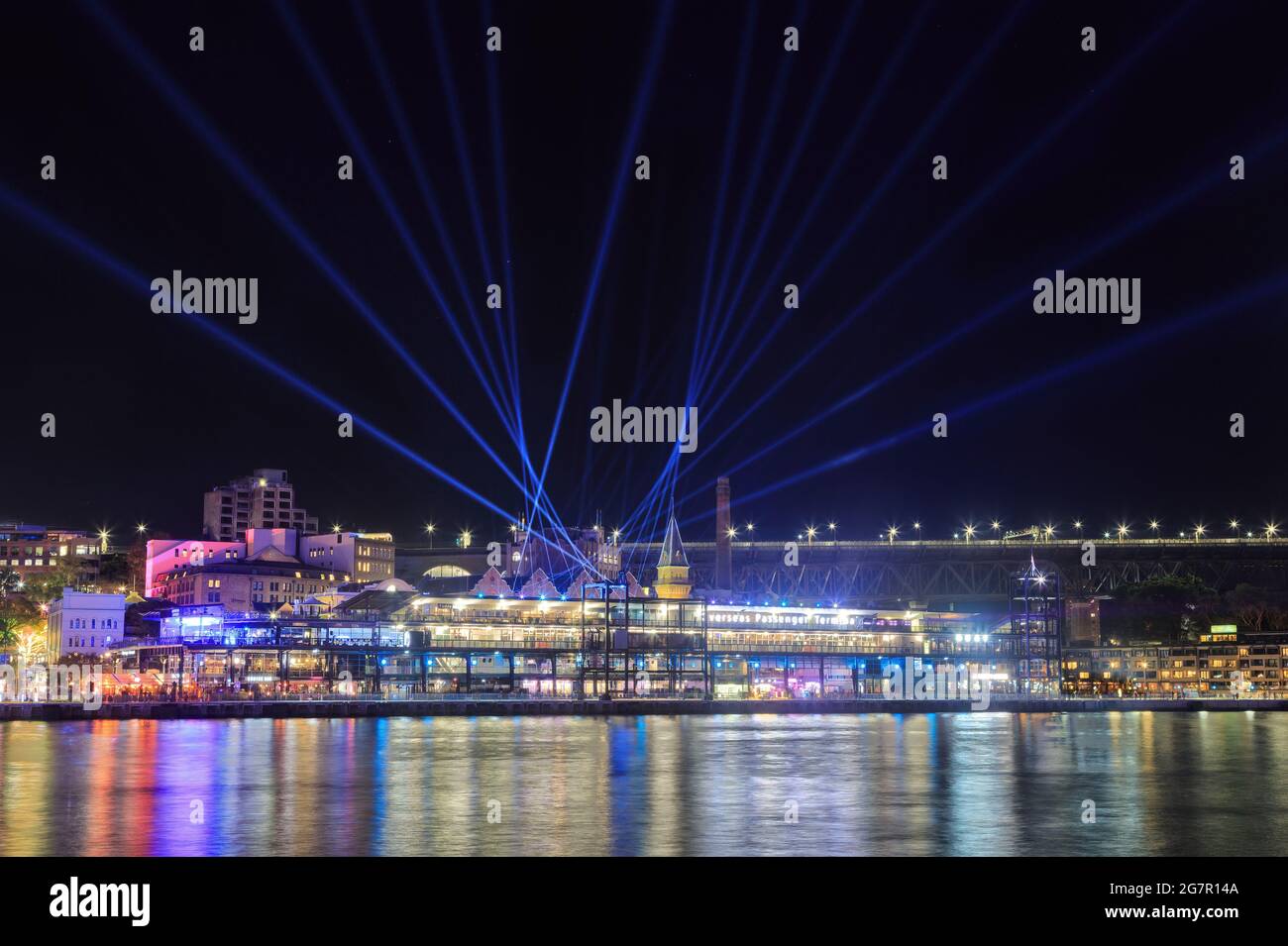 'The Rocks', a waterfront suburb of Sydney, Australia, lit up for the annual Vivid Sydney festival, with searchlights filling the sky Stock Photo
