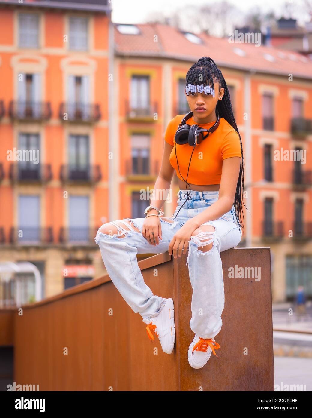 Native American trap dancer with braids wearing an orange shirt and cowboy  pants sitting on the wall Stock Photo - Alamy