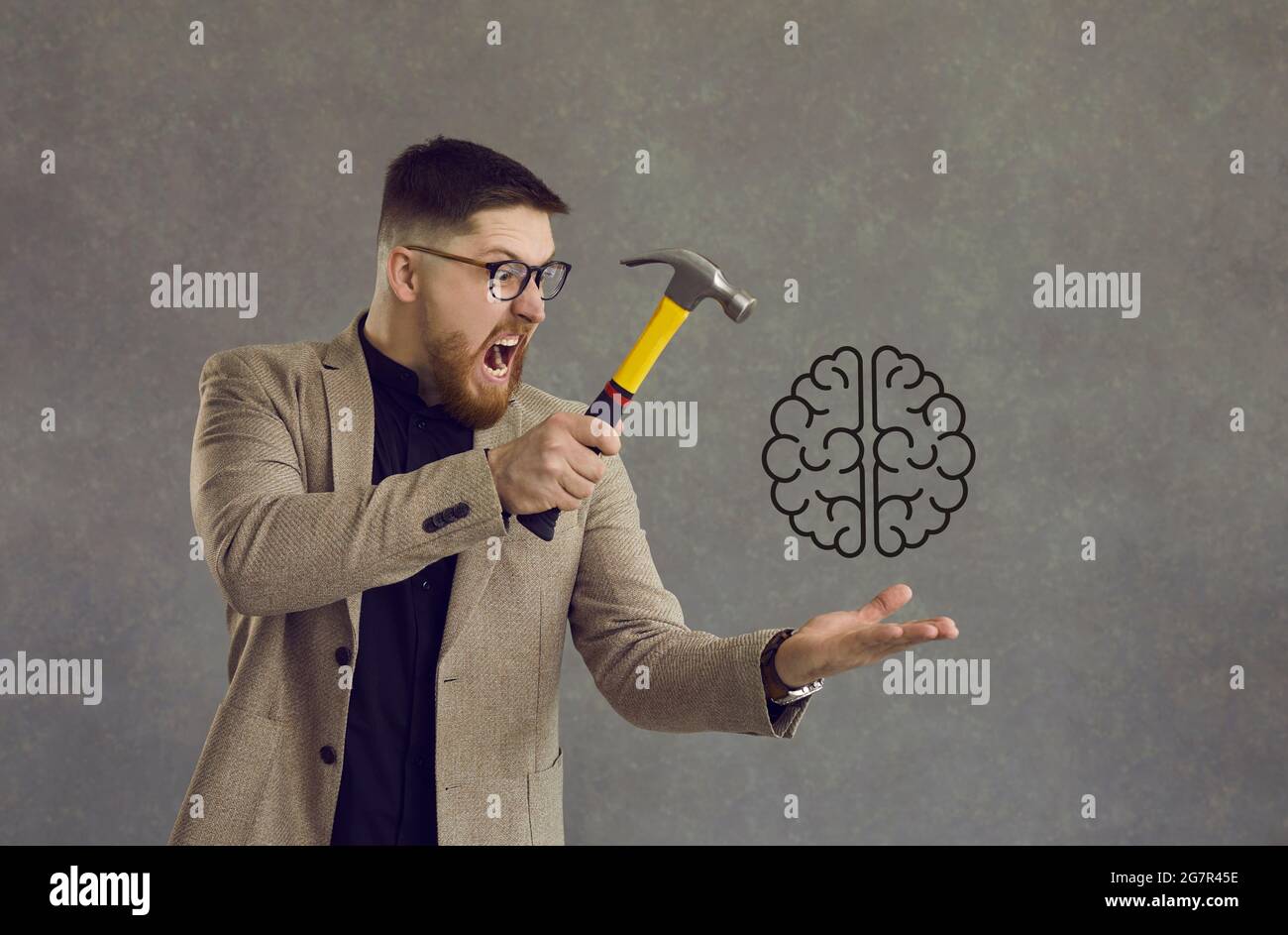 Angry man experiencing mental disorder, stress, or lack of creativity hitting brain with hammer Stock Photo