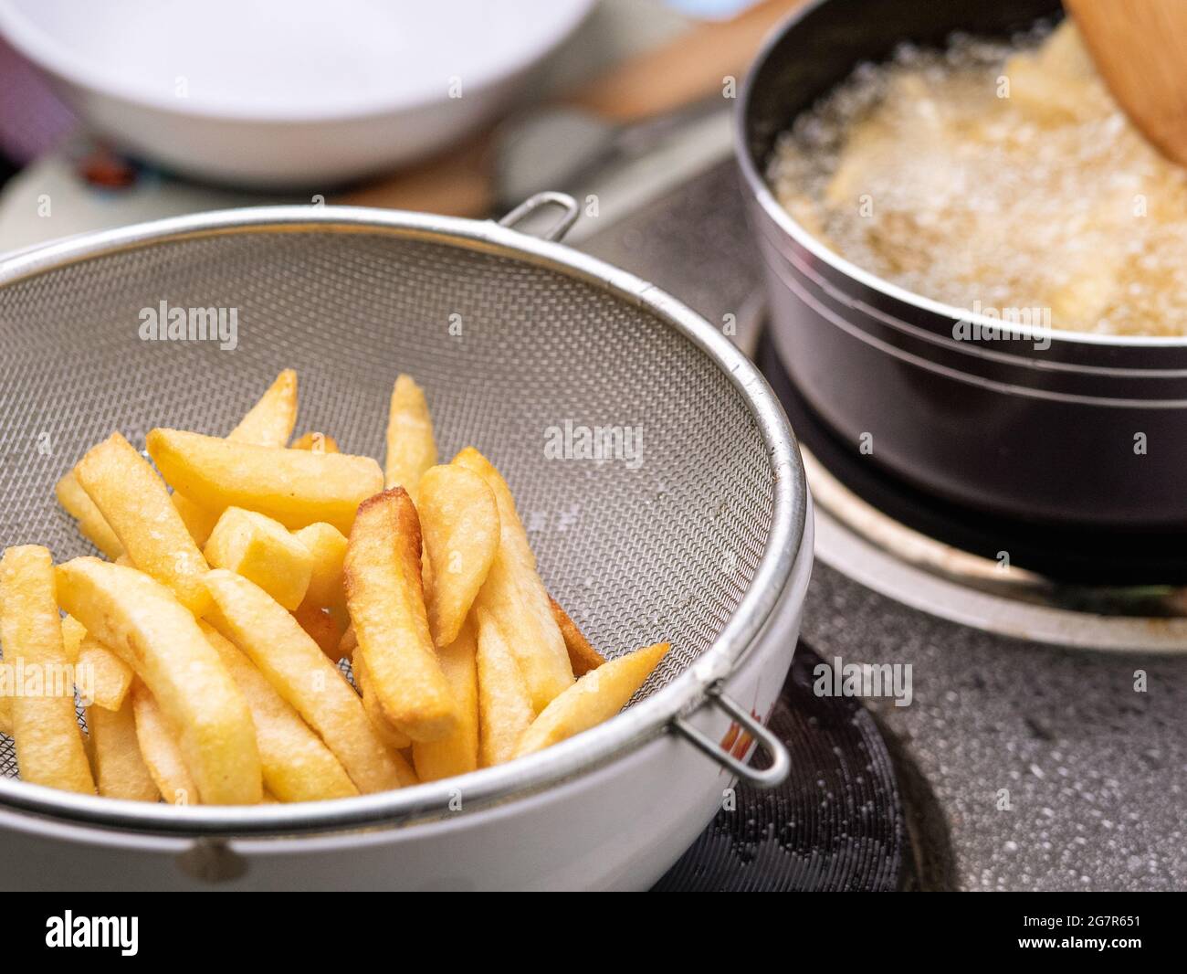 Frying french fries in the fryer in hot oil on the electric stove in