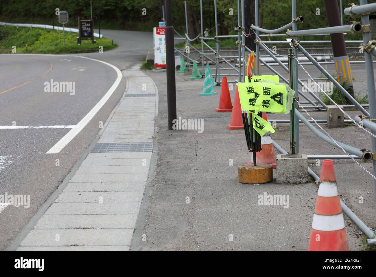 yellow Pedestrian crossing flags, with a street crosswalk ready for use at inawashiro lake. 'Crossing' is written on it in Japanese. Stock Photo