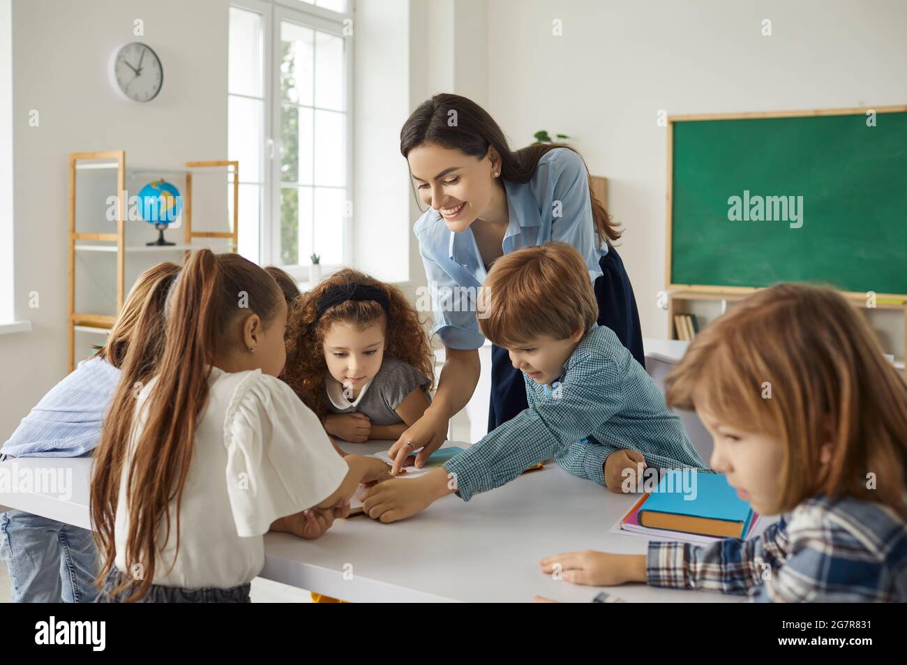 Happy school teacher and little kids reading books and learning new things together Stock Photo