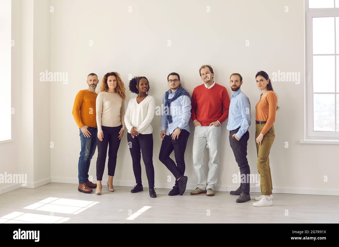 Group of diverse people in casual wear standing together in empty office or studio Stock Photo