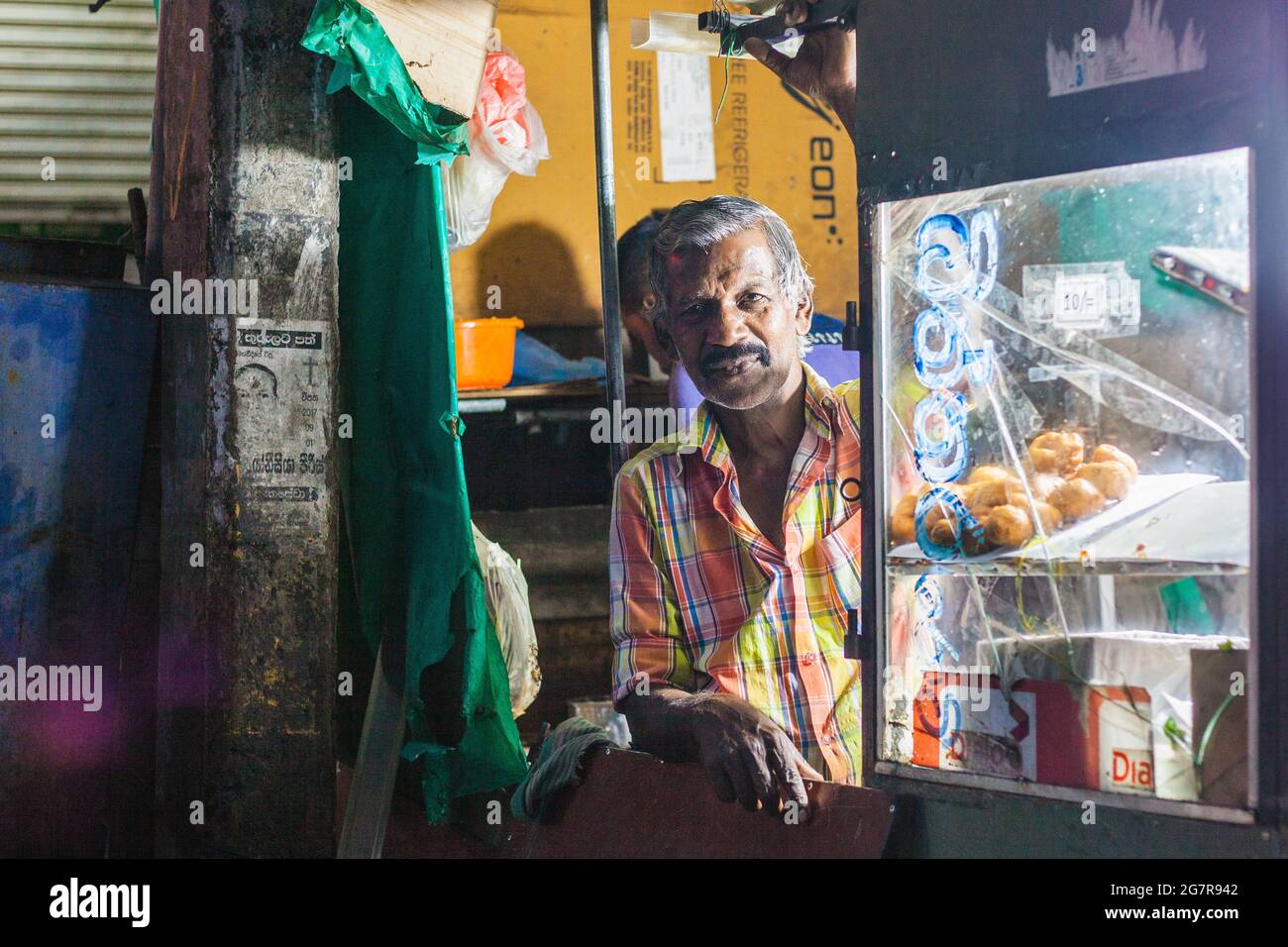 Close up portrait of Sri lankan streetfood trader at kiosk with low lighting (f/2.8), negombo, Sri Lanka Stock Photo