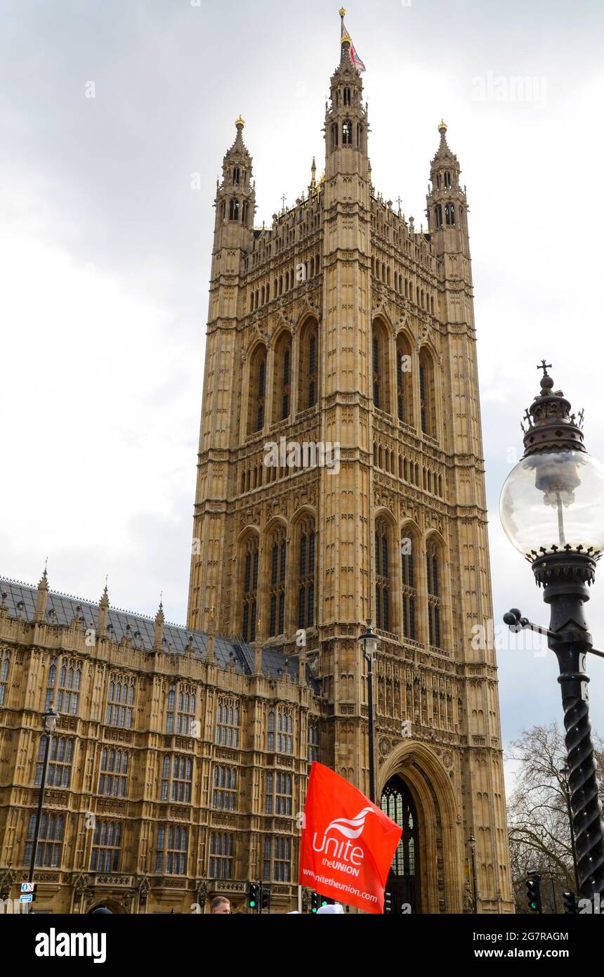 A Unite the Union red flag outside the Houses of Parliament, Palace of Westminster in London, UK, at a protest for lost pensions. Victoria Tower Stock Photo