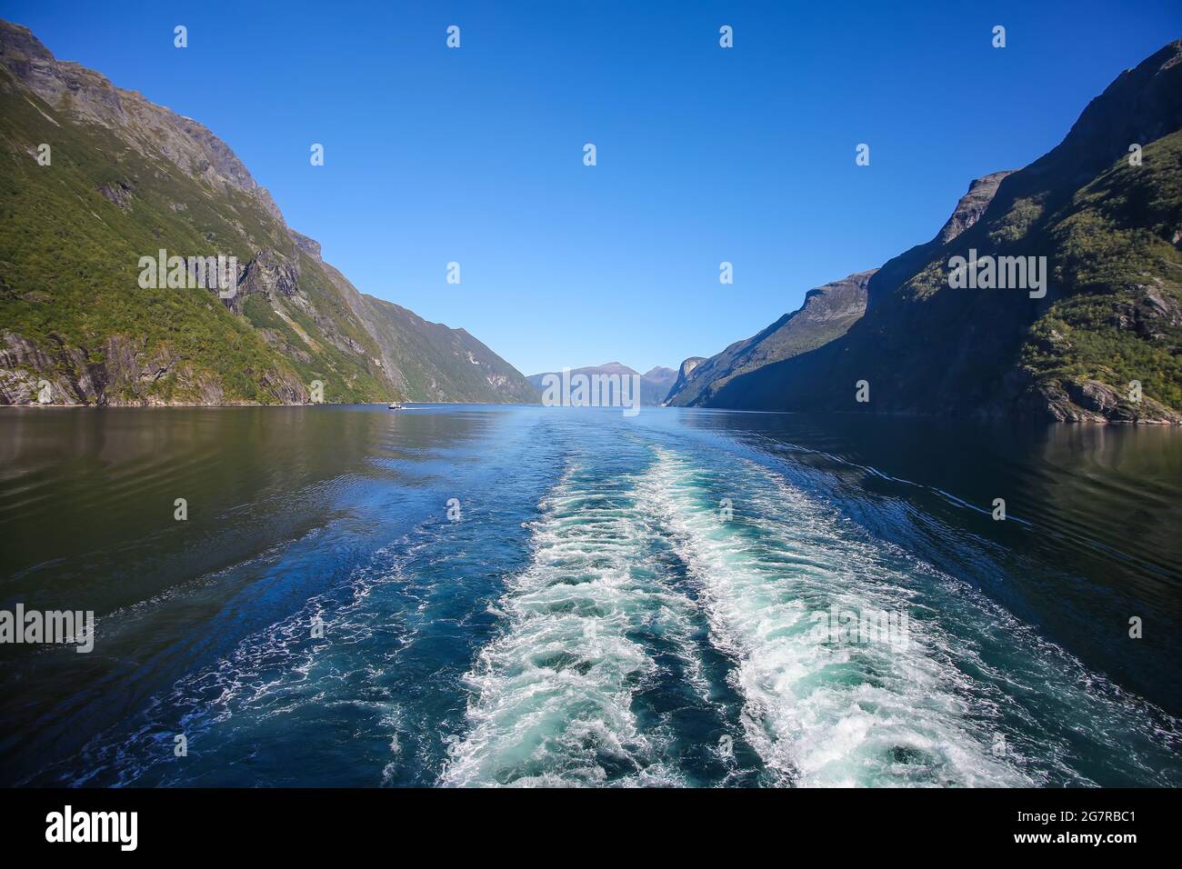 Wake of the ship while scenic cruising down Geiranger fjord. Beautiful landscape with reflections of the mountains in the water on a calm summer day, Stock Photo