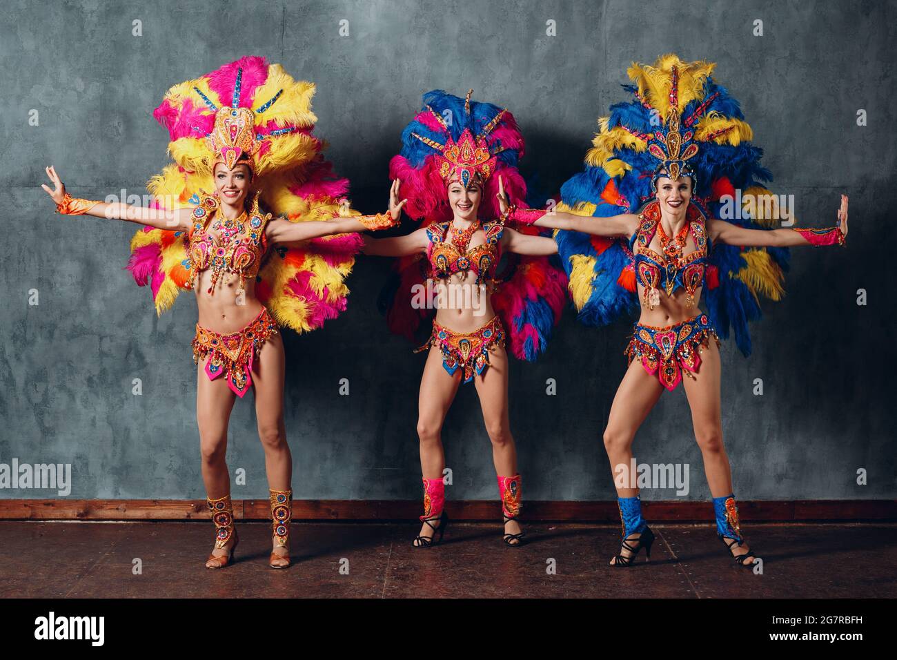 Three Woman in brazilian samba carnival costume with colorful feathers  plumage full lenght hight gray vintage background Stock Photo - Alamy