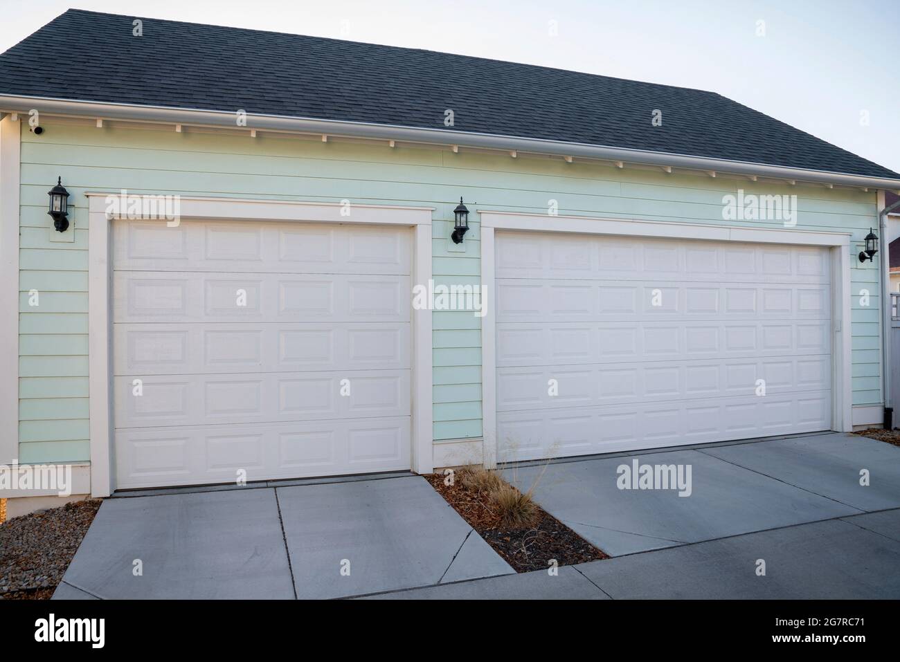 Threecar garage exterior with mint green vinyl wall siding Stock Photo