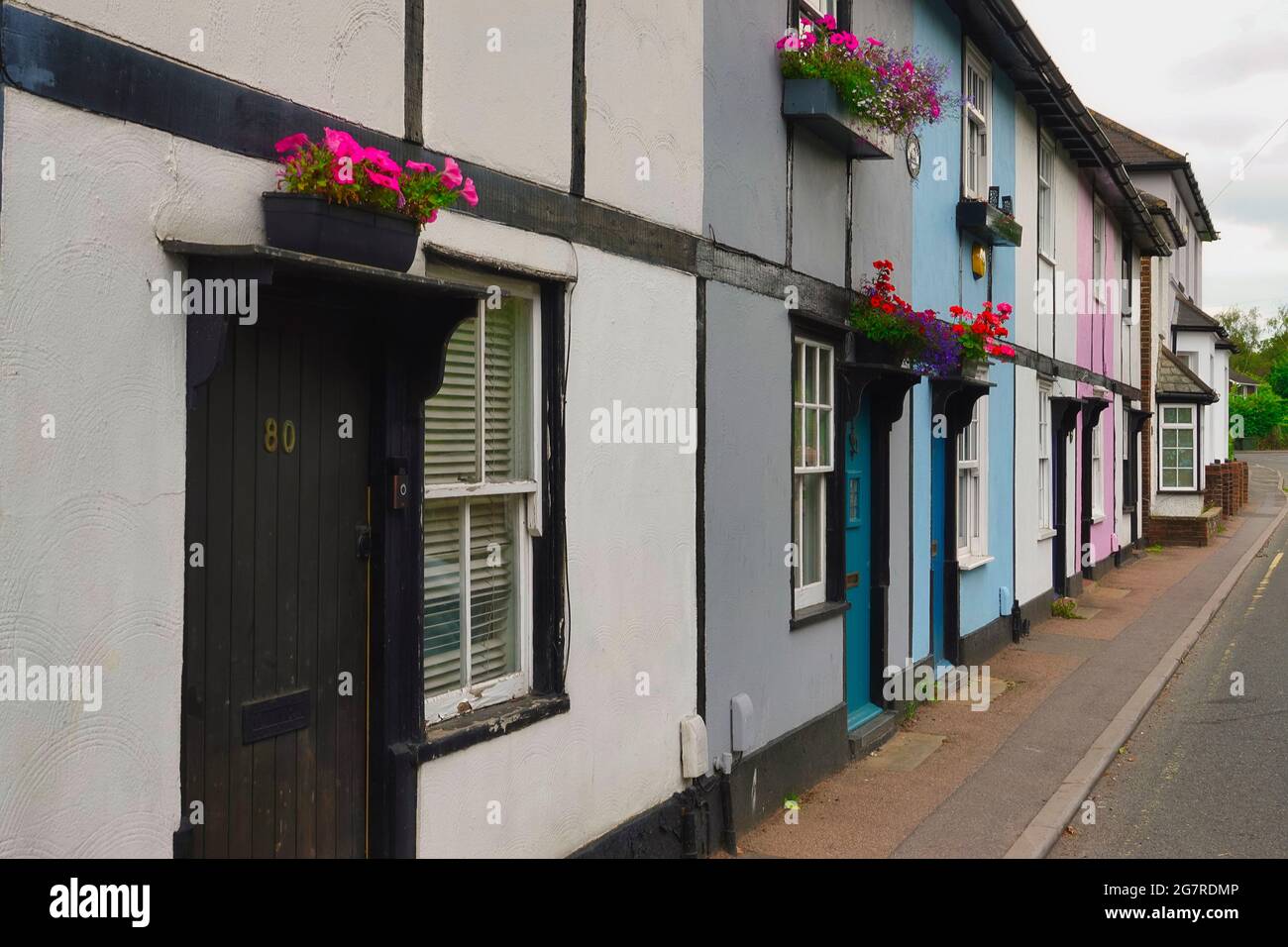 Traditional English olde world cottages painted in multi colours with floral hanging baskets - seen in Surrey UK Stock Photo
