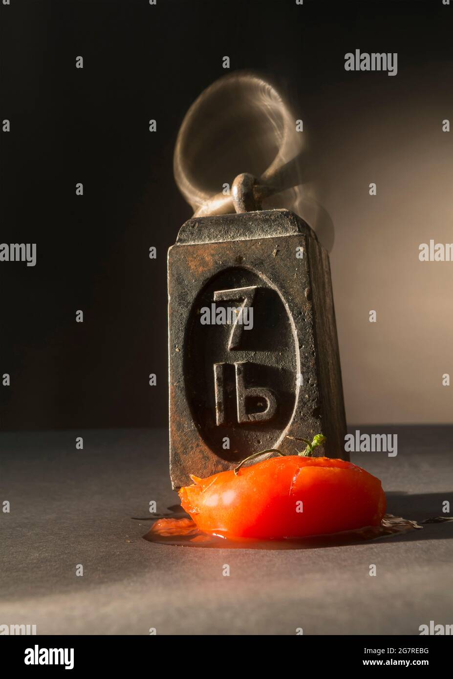 A seven pound weight squashing a tomato Stock Photo