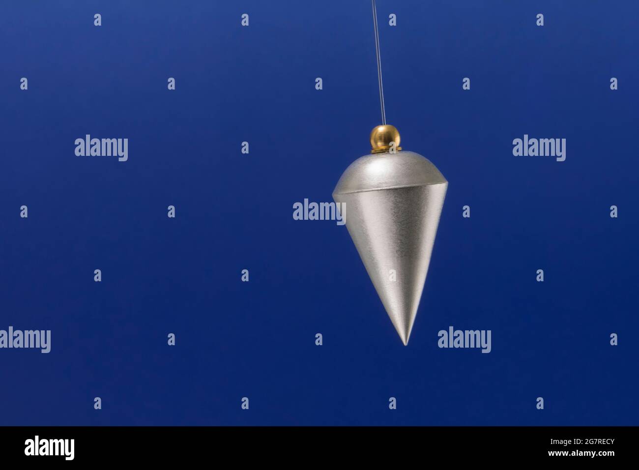 A silver pendulum swinging from side to side Stock Photo