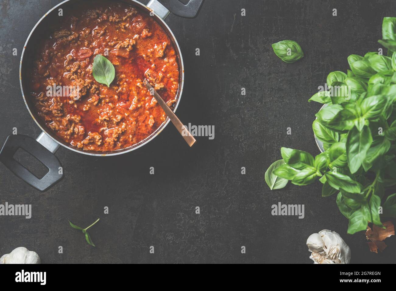 Food background with sauce bolognese in black cooking pot on dark background. Top view Stock Photo