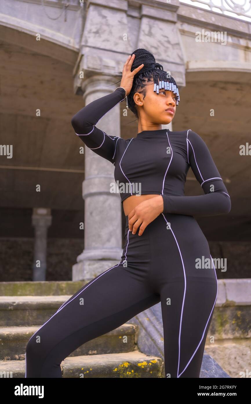 Dominican female with braids in a black body suit standing next to a  beautiful building with columns Stock Photo - Alamy