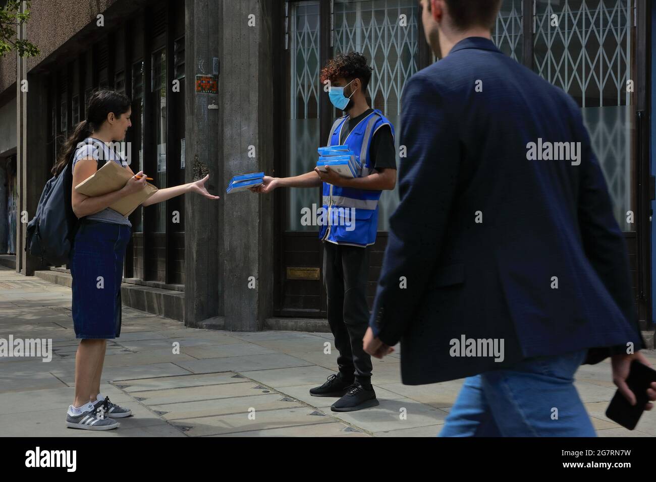 Londom (UK), 14 July 2021: An NHS support worker hands out covid self testing kits to members of the public on the streets of central London Stock Photo