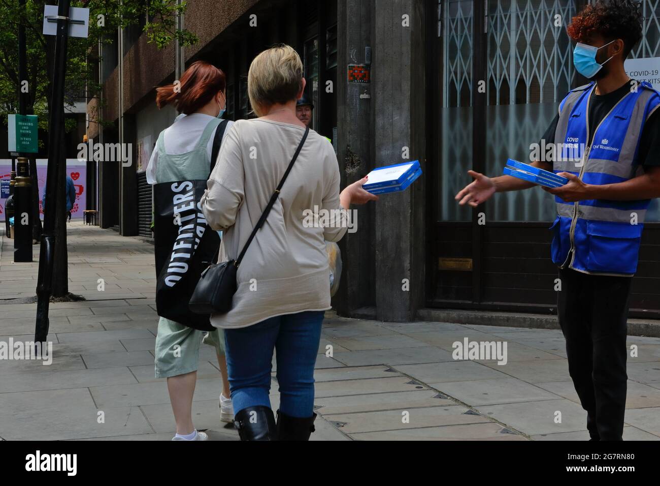 Londom (UK), 14 July 2021: An NHS support worker hands out covid self testing kits to members of the public on the streets of central London Stock Photo