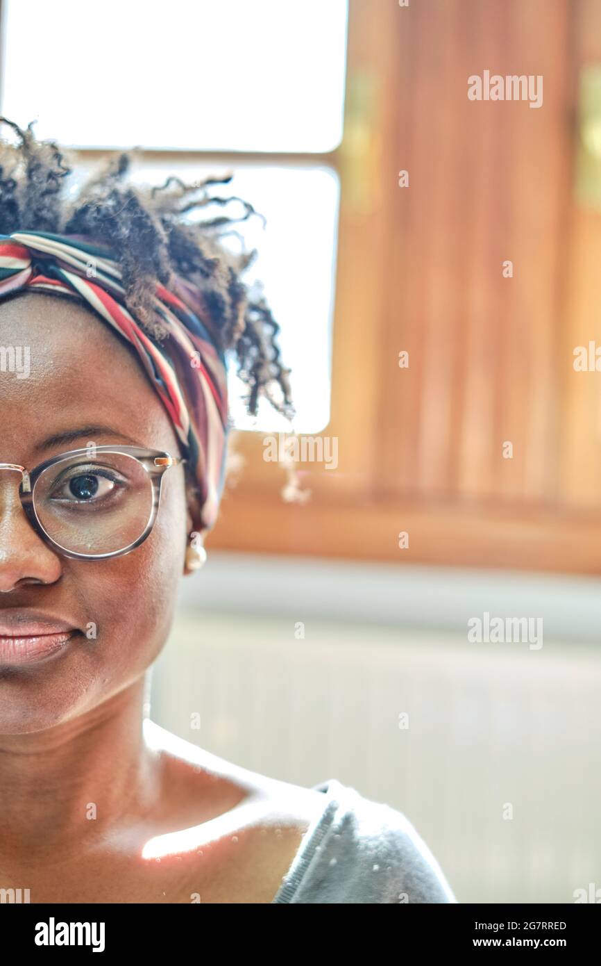 Closeup portrait of a young black woman in glasses and afro hairstyle indoor in a room. Lifestyle concept. Stock Photo