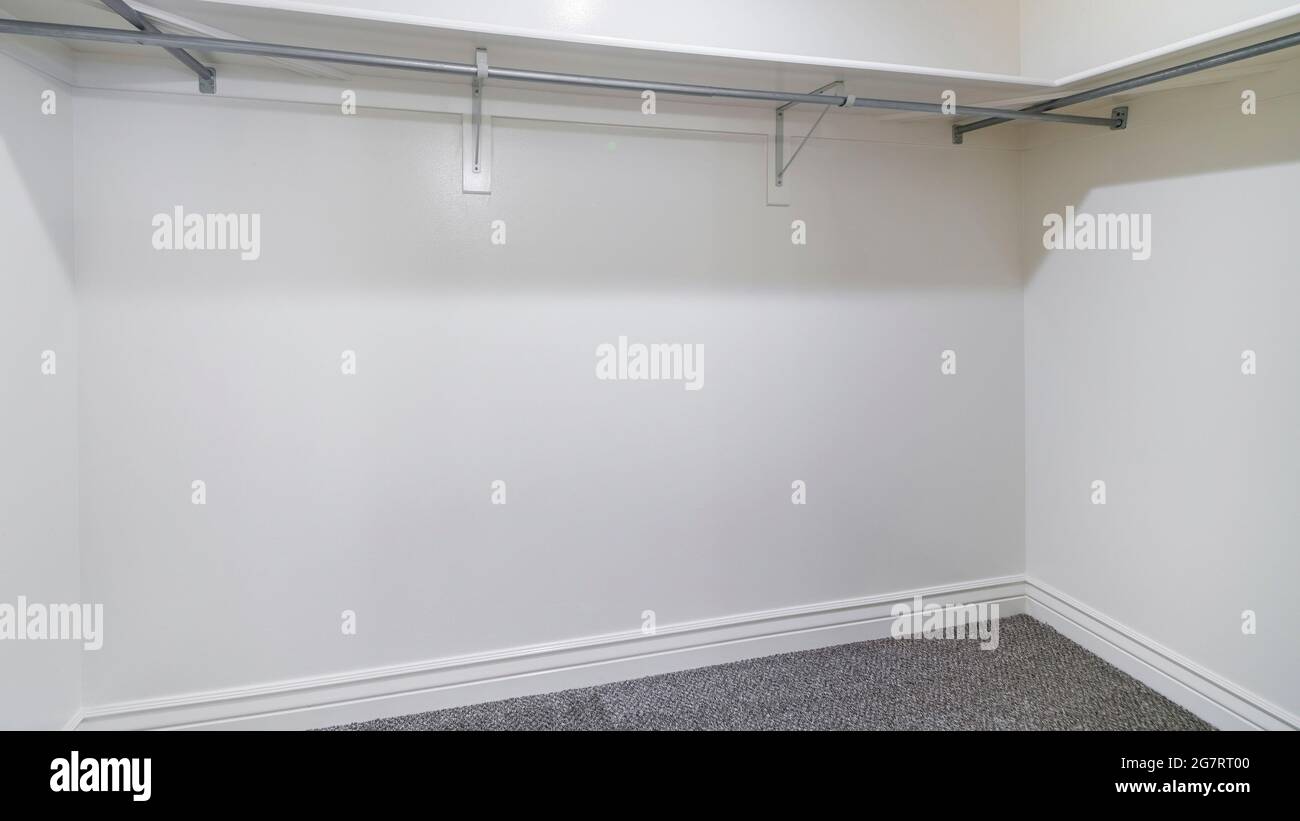 Pano Empty walk in closet with metal hanging rods and wooden shelves ...