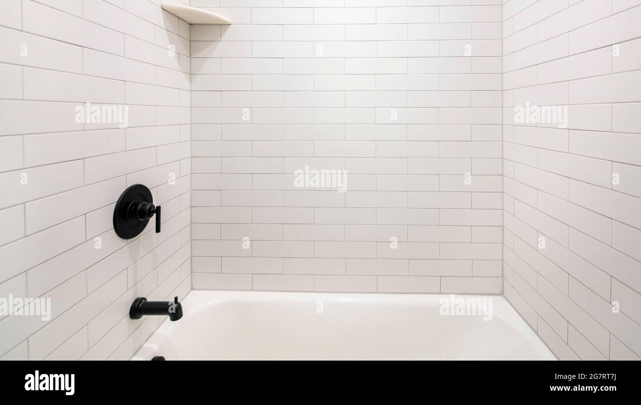 Pano Alcove bathtub with black plumbing fixtures and white subway tiles