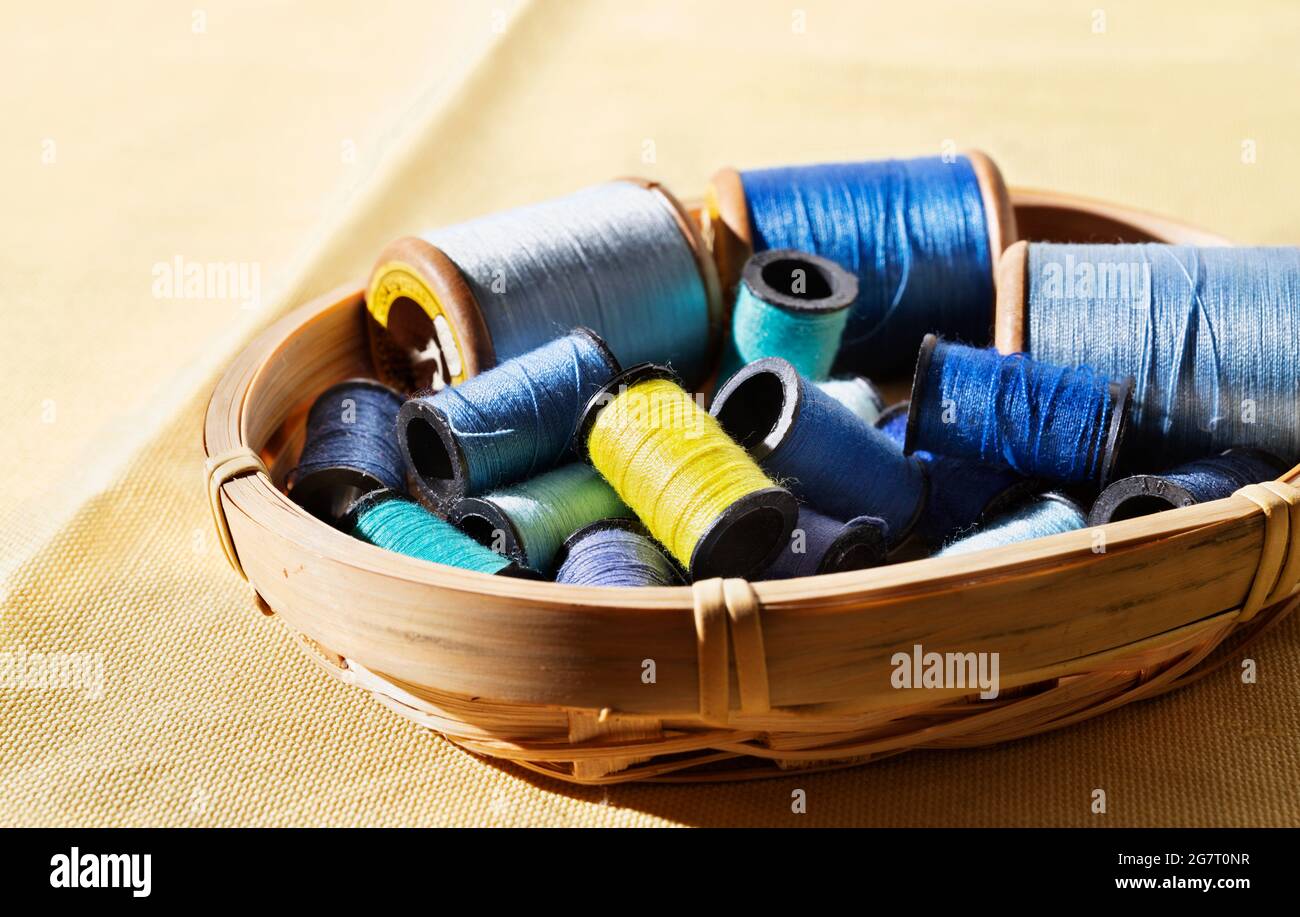 Spools of blue thread and one yellow spool in basket ,different size spools Stock Photo