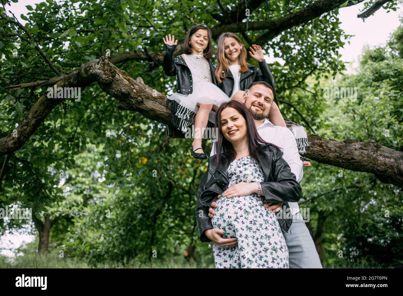 Attractive pregnant woman with her husband and two daughters posing on
