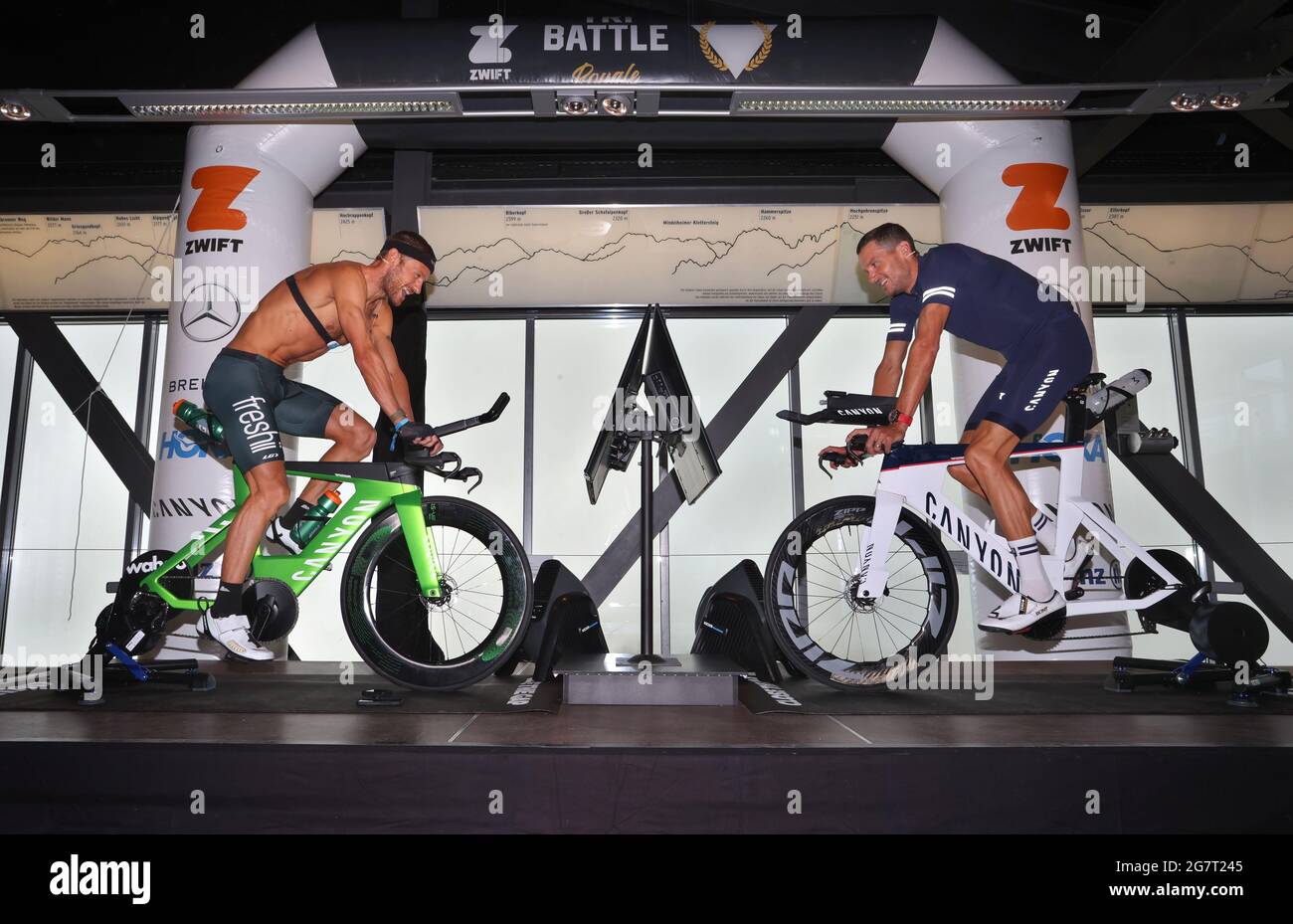 16 July 2021, Bavaria, Oberstdorf: Jan Frodeno, triathlete from Germany (r)  and Lionel Sanders,triathlete from Canada, sit on the summit station of the  Fellhorn, during a press conference, on a ZWIFT Ride.
