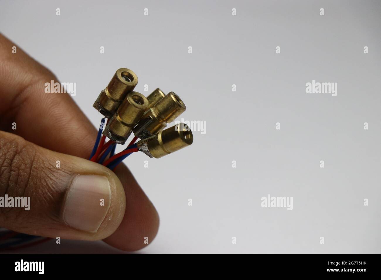 Group of copper case red dot laser diodes held in hand. Electronic components for laser light experiments Stock Photo