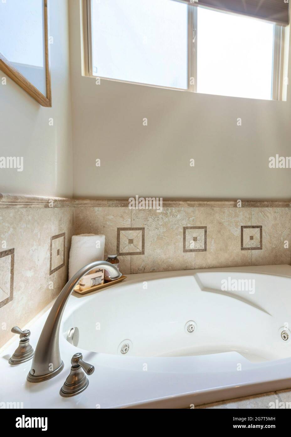 Vertical Bathtub on a deck with patterned tiles and windows Stock Photo