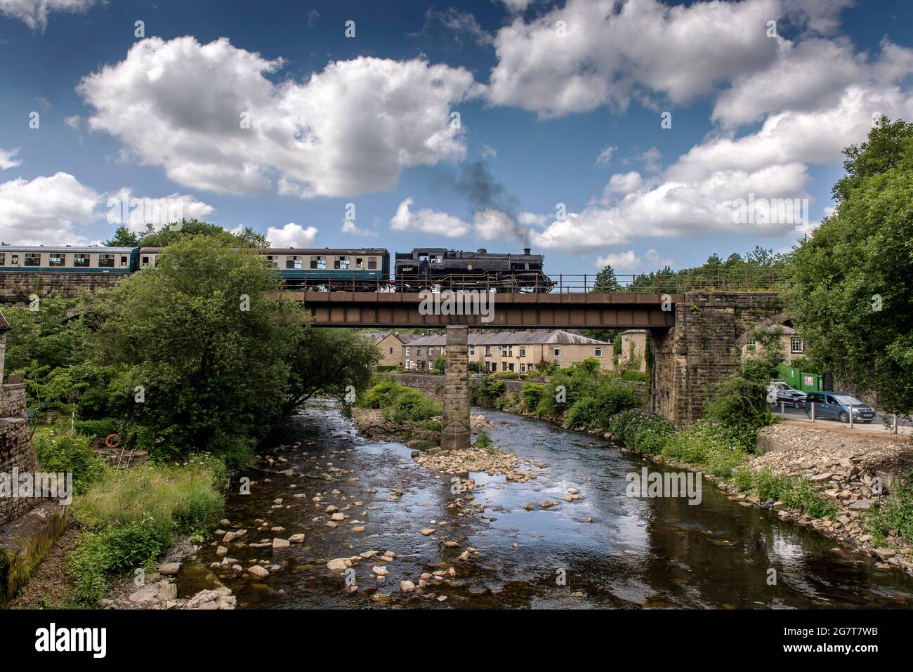 Lancashire, UK, Friday July 16, 2021. A steam engine from the East Lancashire Railway carries passengers across the River Irwell viaduct in the pretty village of Summerseat in Bury under glorious blue skies. Forecasters are predicting that the hot weather will continue through the weekend and into next week in the north west of England. Credit: Paul Heyes/Alamy Live News Stock Photo