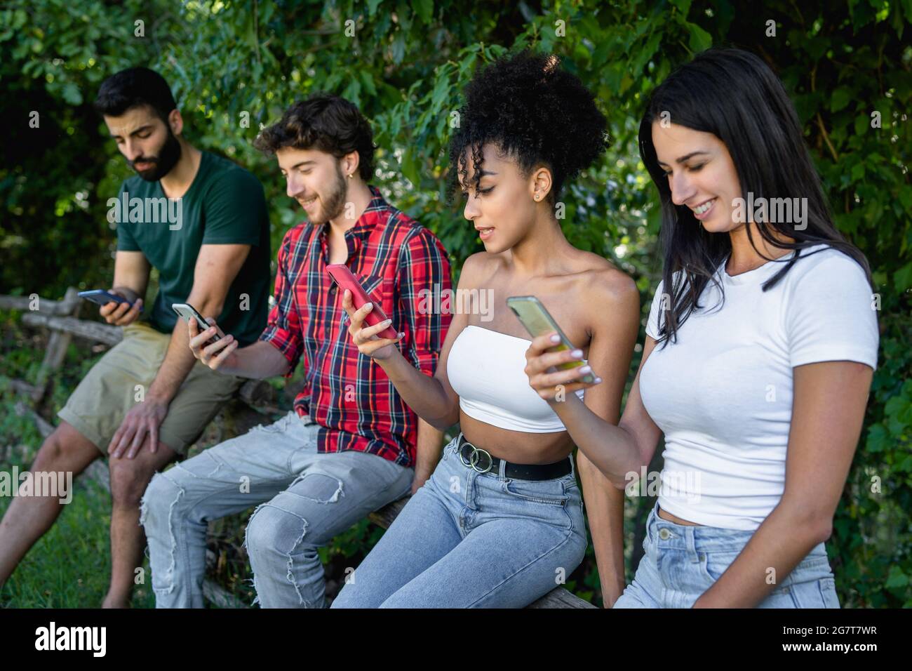 Millennials using smartphone in the countryside. Multiracial group of young people using tech in nature concept. Stock Photo