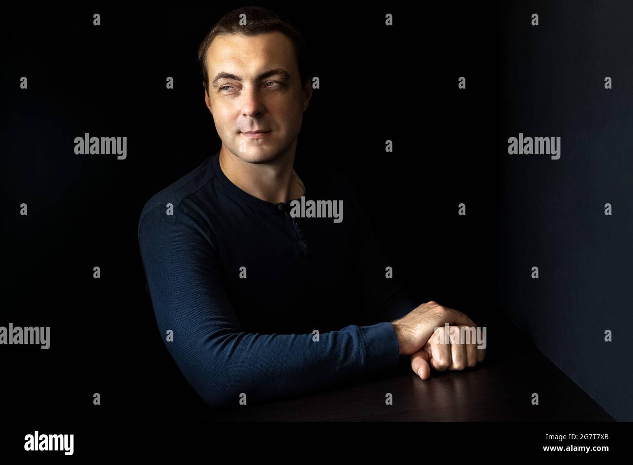 Portrait of a young man in a blue shirt in a dark key. Stock Photo