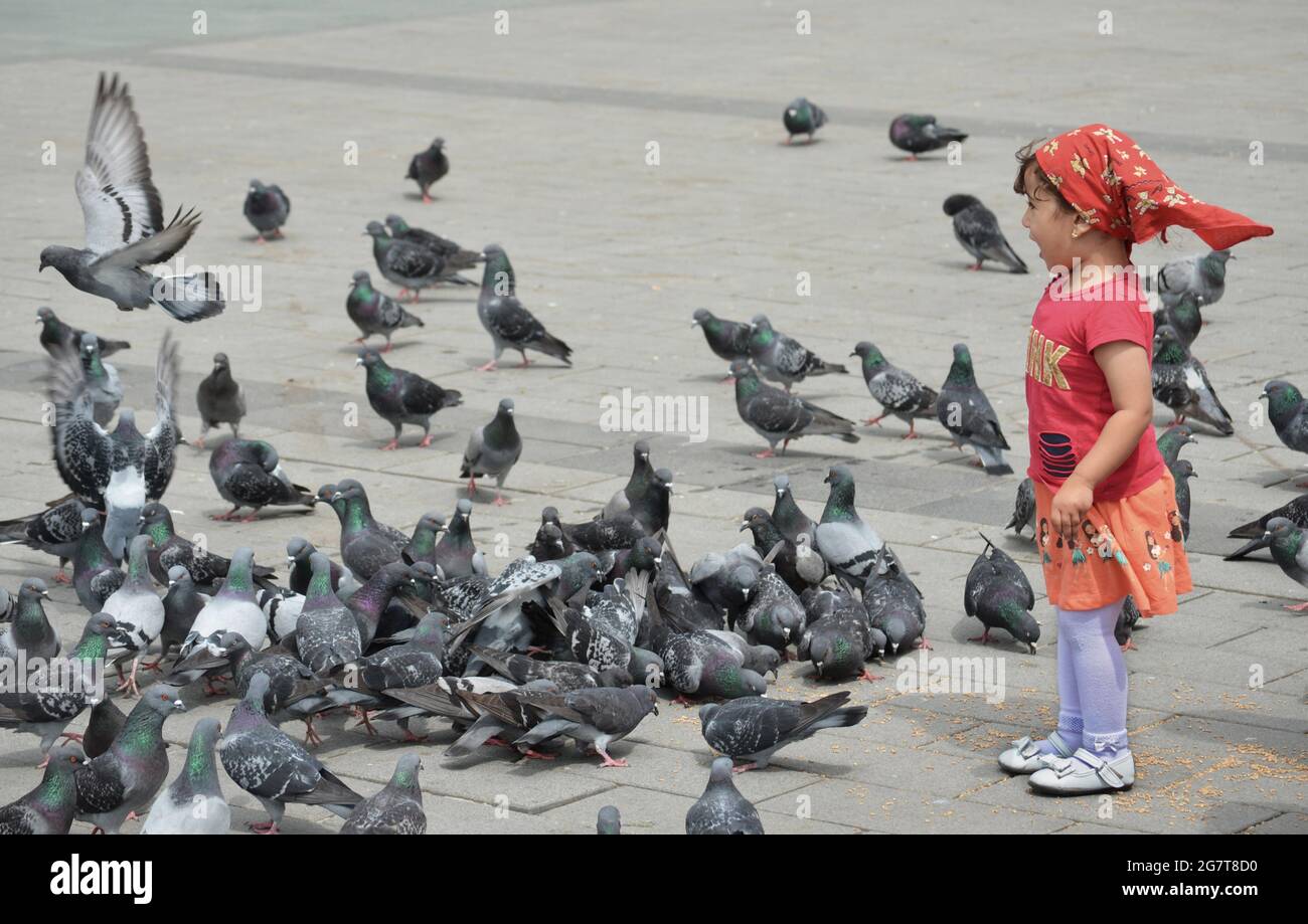 An excited child playing with pigeons in Taksim Square in Istanbul Stock Photo