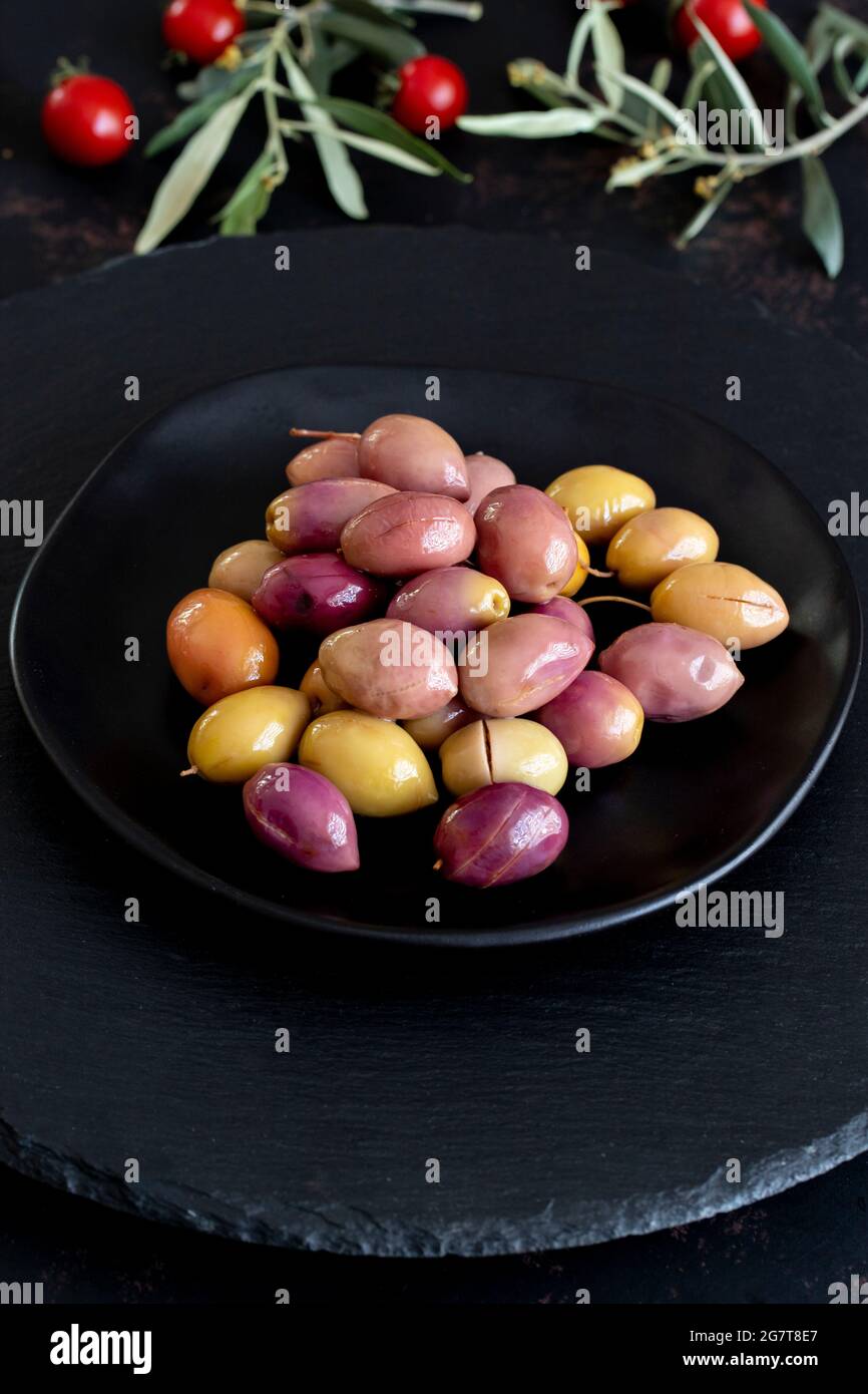 Mixed marinated olives (green and purple) on dark background. Tasty
