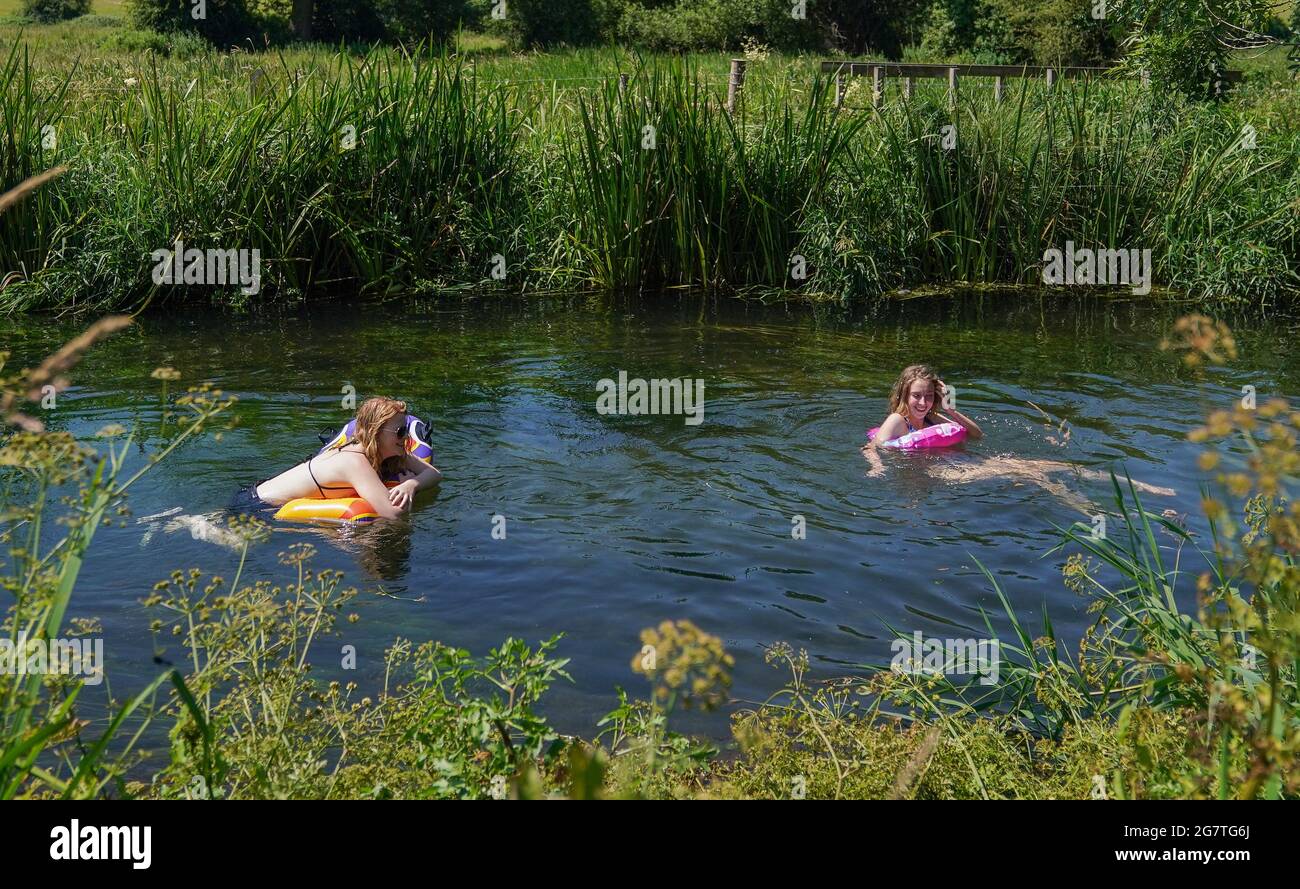 Two people use inflatables to make their way along the river Itchen near to Twyford in Hampshire. Picture date: Friday July 16, 2021. Stock Photo