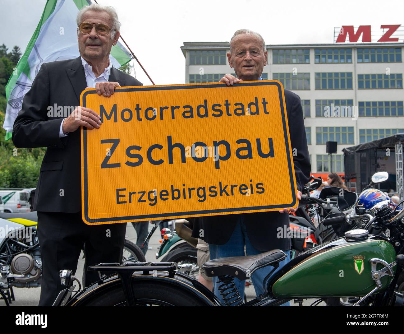 Zschopau, Germany. July 16 2021: Jörgen S. Rasmussen (l), grandson of the eponymous founder of the Zschopau engine works, and Carl Hahn, former Chairman of the Board of Management of Volkswagen, stand by a DKW SB 200 from 1936 in front of the former DKW and MZ motorcycle factory in Zschopau with the new entrance sign to the motorcycle town. Flanked in style by hundreds of two-wheelers, mainly from DKW and MZ production, the town has now been awarded the title of Motorcycle Town. Motorcycles were built in the Saxon city between 1922 and 2016. Credit: dpa picture alliance/Alamy Live News Stock Photo