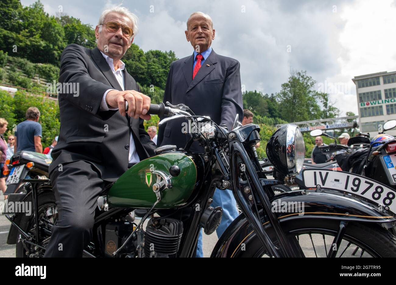 Zschopau, Germany. July 16 2021: Jörgen S. Rasmussen (l), grandson of the eponymous founder of the Zschopau engine works, sits next to Carl Hahn, former Chairman of the Board of Management of Volkswagen, on a 1936 DKW SB 200 in front of the former DKW and MZ motorcycle plant in Zschopau. Both guests of honour watched the awarding of the name 'Motorcycle City' to Zschopau. Flanked in style by hundreds of two-wheelers, mainly from DKW and MZ production, the town was now awarded the title. Motorcycles were built in the Saxon town between 1922 and 2016. Credit: dpa picture alliance/Alamy Live News Stock Photo