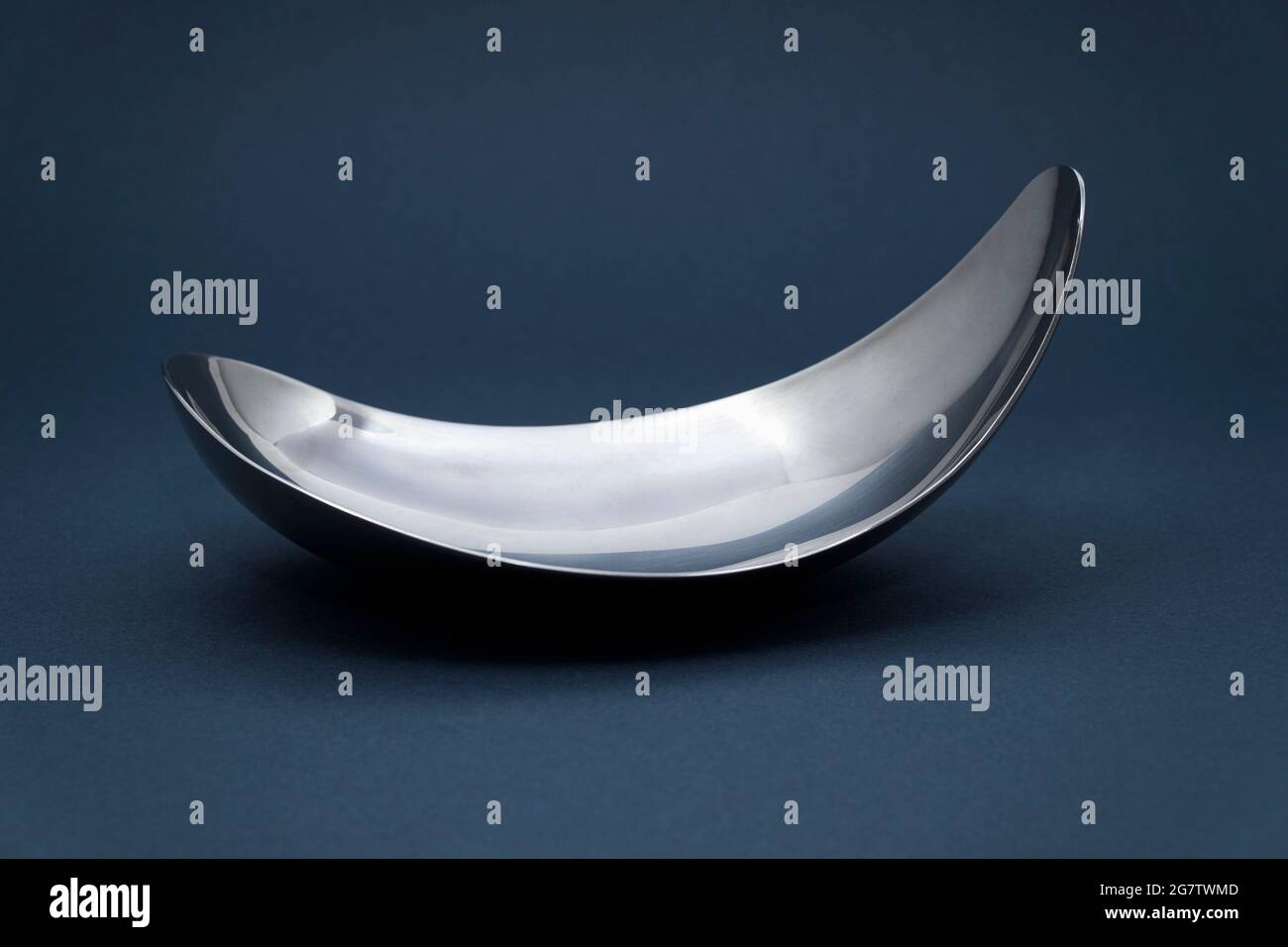 Empty metal silver plate on dark grey background. Stock Photo