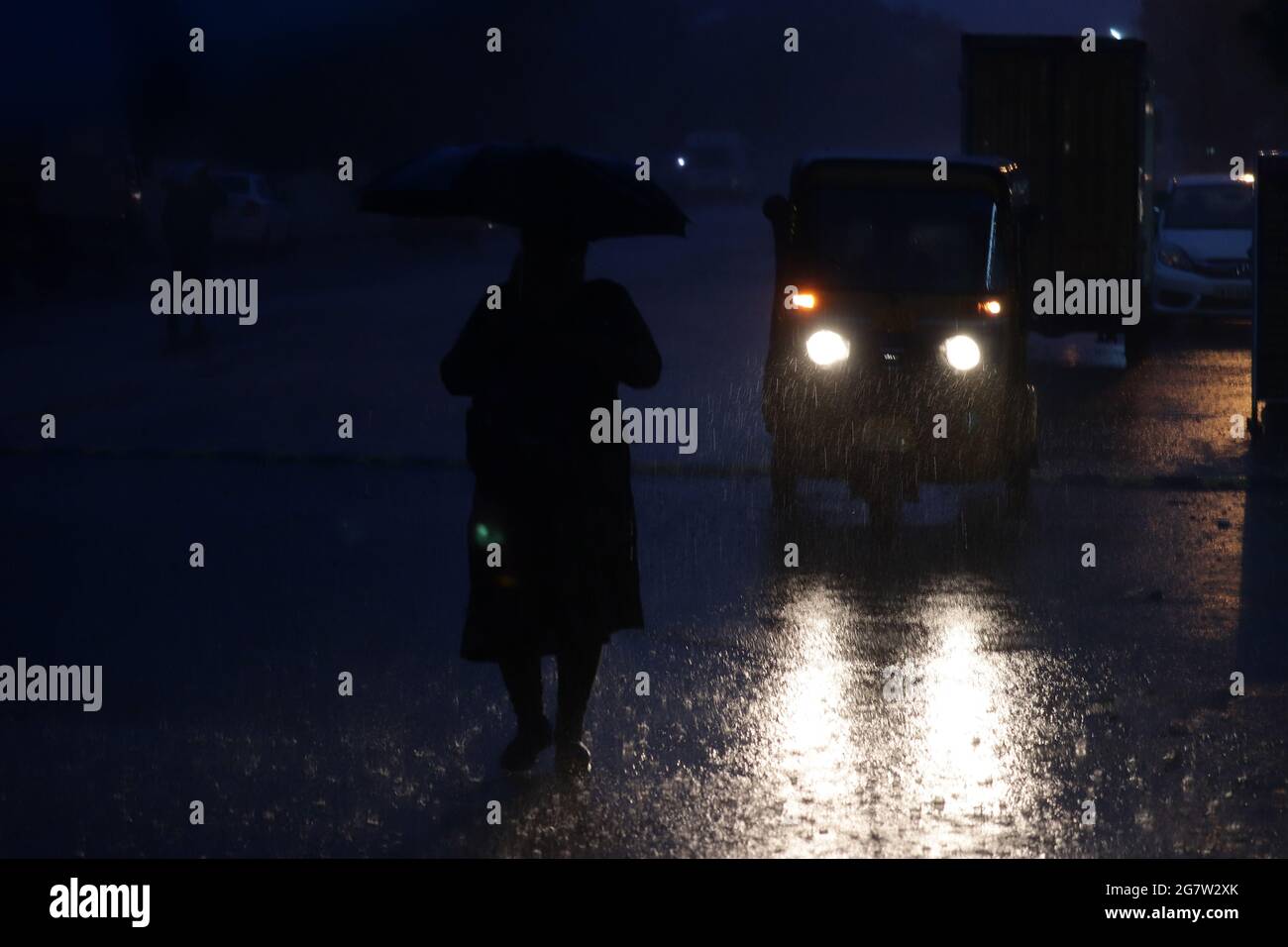 Chennai, Tamil Nadu, India. 16th July, 2021. During a heavy rainstorm, a woman takes shelter under an umbrella while walking down a street in Chennai. Credit: Sri Loganathan/ZUMA Wire/Alamy Live News Stock Photo