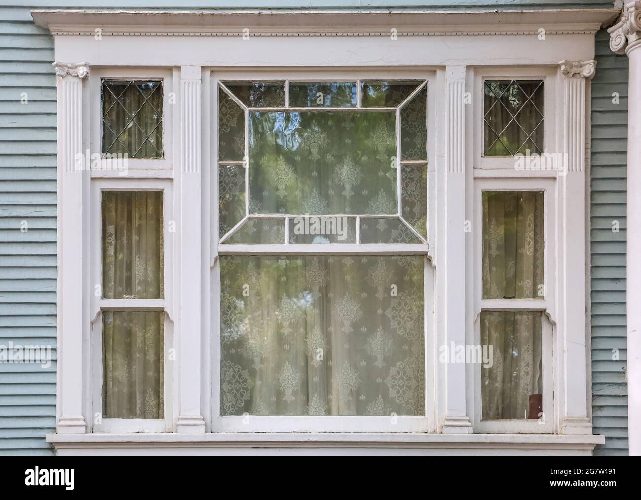 Antique detailed beveled window on a classic Victorian house Stock Photo