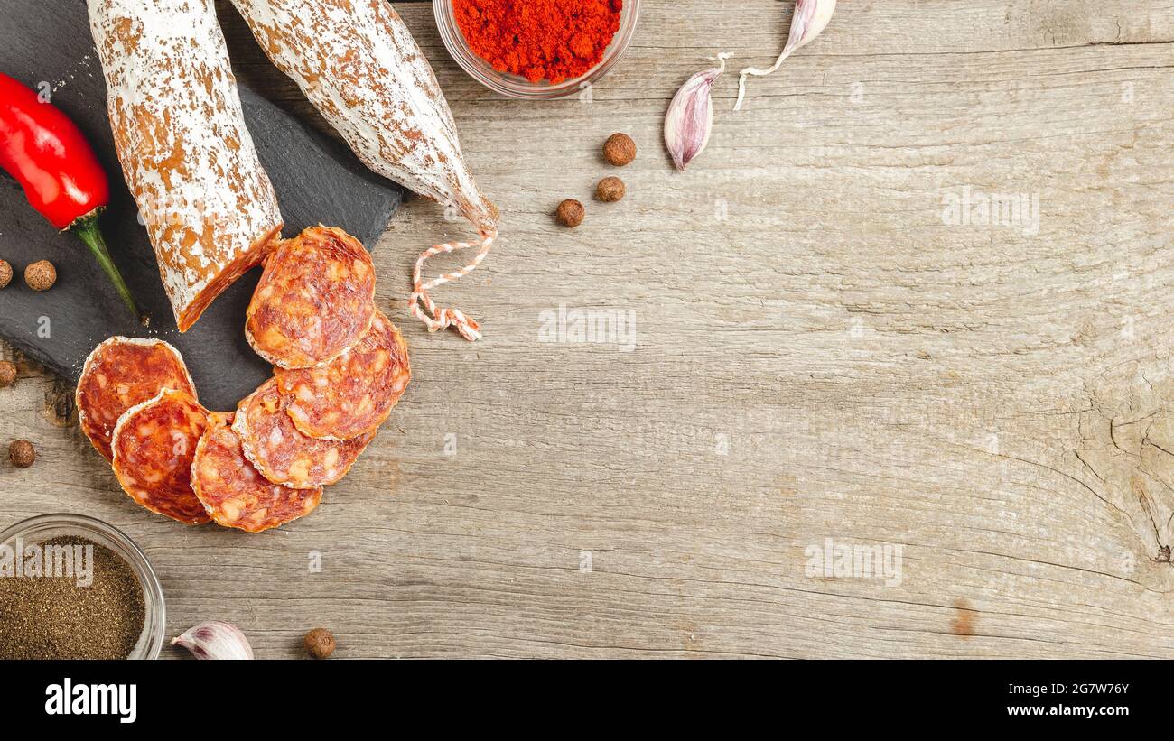 Sliced Chorizo Sausage with Penicillium Edible Mold on the outside on a wooden background with smoked paprika, chili, garlic and black pepper. Copy sp Stock Photo