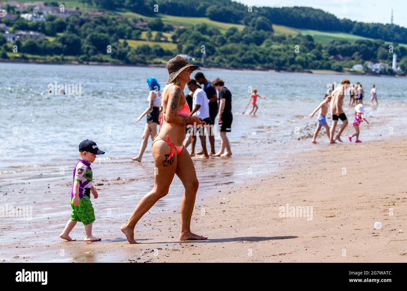 Dundee, Tayside, Scotland, UK. 16th July, 2021. UK Weather: Hot sunny weather sweeping across North East Scotland with maximum temperature 29°C. Beach-goers take the day out soaking up the warm glorious summer sunshine along Broughty Ferry beach in Dundee. A mother and her son playing about in the river Tay. Credit: Dundee Photographics/Alamy Live News Stock Photo