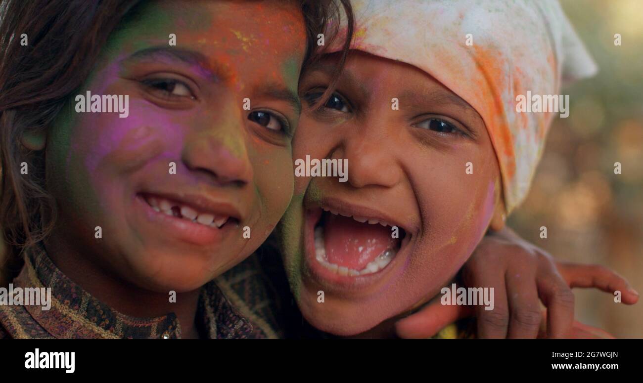 Closeup shot of South Asian children with painted colorful faces during the Indian Holi Festival Stock Photo