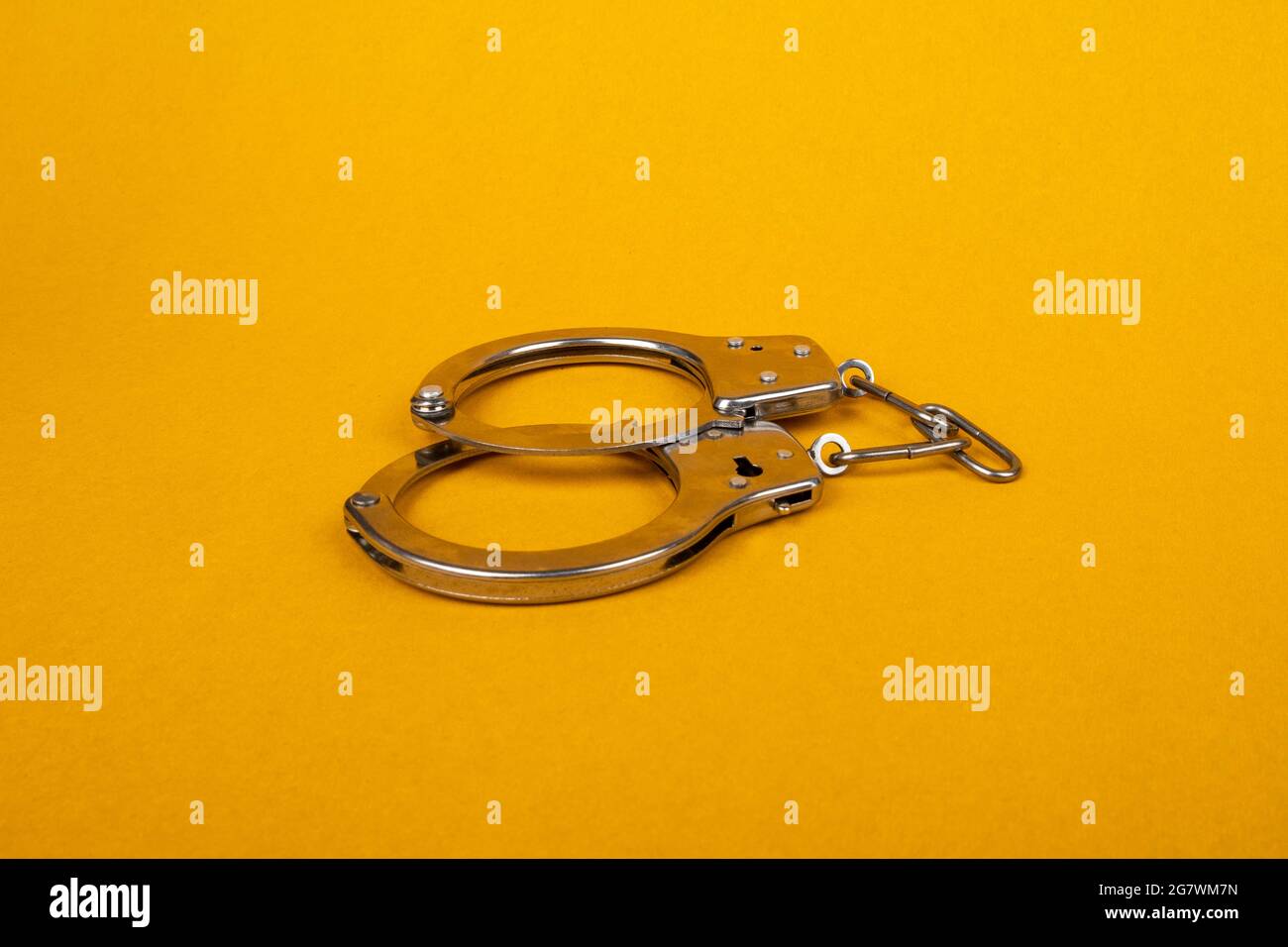 handcuffs on yellow background, concept of arrest Stock Photo - Alamy